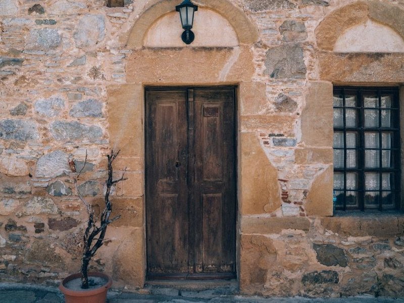 Porte d'entrée bois de caractère posée dans un encadrement en pierre dorée sur une maison du village de Curis-au-Mont-d'Or