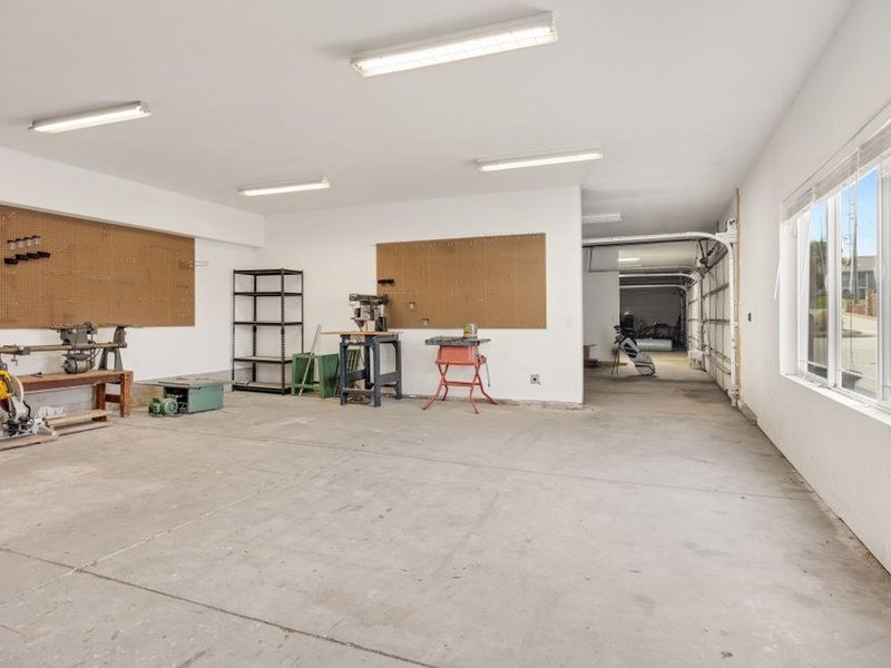 Porte de garage sectionnelle motorisée blanche à panneaux relevée au plafond dans le garage d'un pavillon récent à Décines