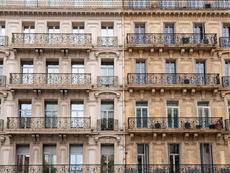 Grands vantaux vitrés d'une porte-fenêtre haussmannienne ouvrant sur un balcon en ferronnerie dans un immeuble bourgeois de Lyon 6