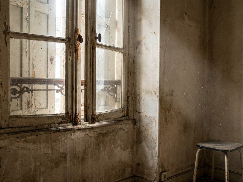 Ancienne fenêtre bois fatiguée qui ferme mal dans un studio étudiant vide d'immeuble ancien à la Guillotière, Lyon 7e