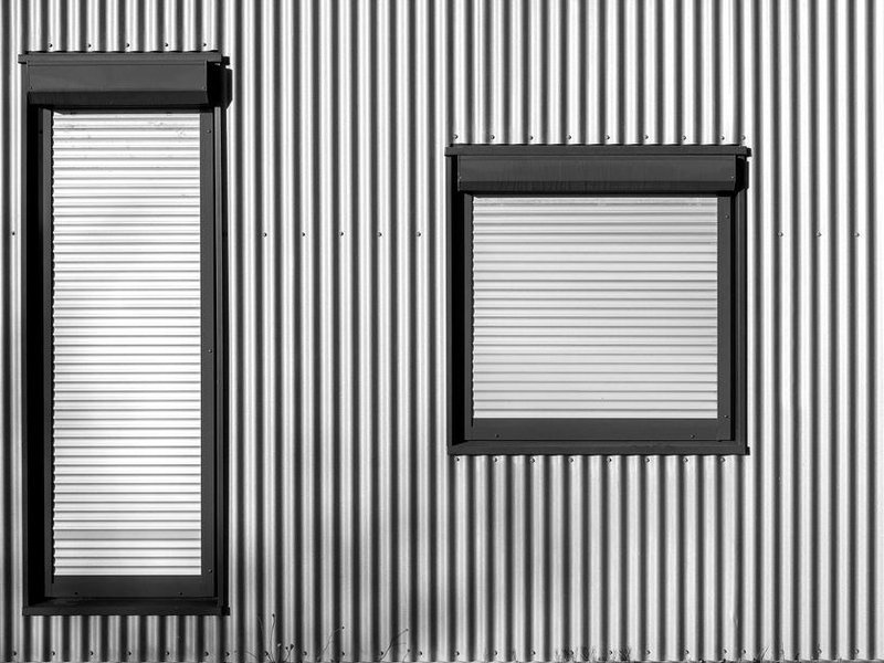 Persiennes métalliques repliables et volets battants d'époque repeints sur un immeuble Art déco de Monplaisir à Lyon 8
