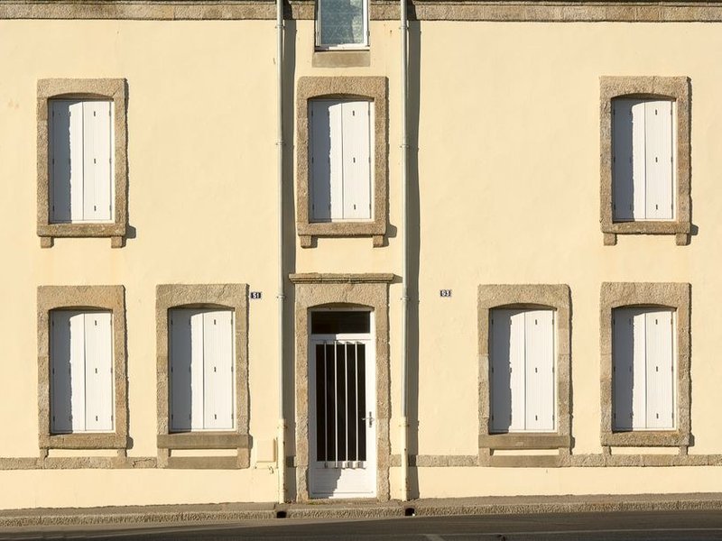 Menuiseries et volets bois d'une façade en pierre du vieux village de Millery
