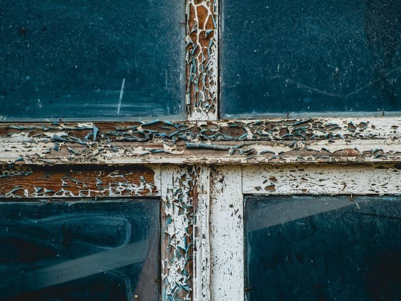 Ancienne fenêtre bois d'origine grisée avec mastic craquelé sur un pavillon des années 80 à Mions, prête à être remplacée