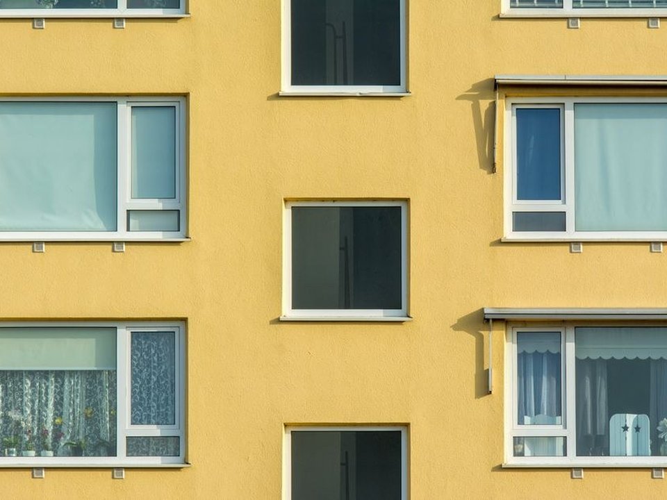 Menuisier posant une fenêtre à la teinte conforme à la façade sur un immeuble de copropriété de standing à Sainte-Foy-lès-Lyon