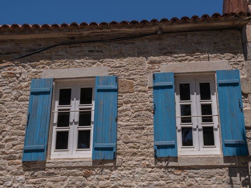 Fenêtre bois au dessin d'époque d'une maison de pierre du vieux village de Sathonay-Village, posée dans un tableau en pierre le long d'une ruelle du bourg perché