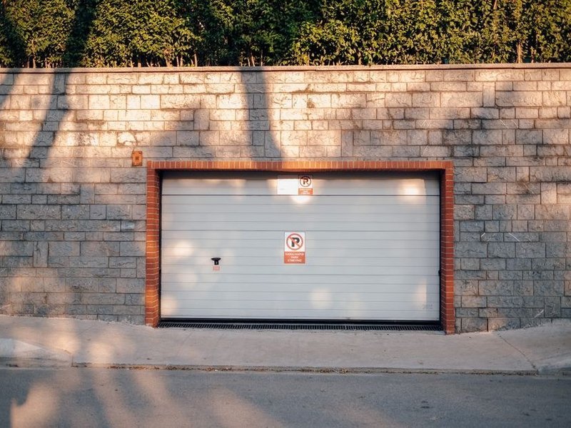 Portail coulissant et porte de garage à l'entrée d'un terrain en pente d'une maison de coteau à Ternay