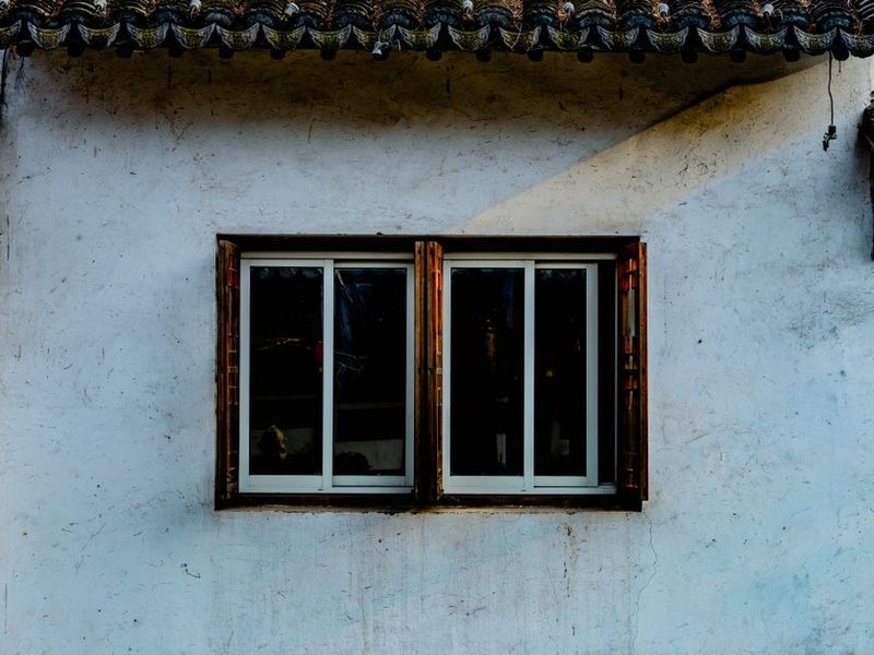 Fenêtre bois à profils fins et porte ancienne d'une maison de village en pierre du bourg de Toussieu à rénover