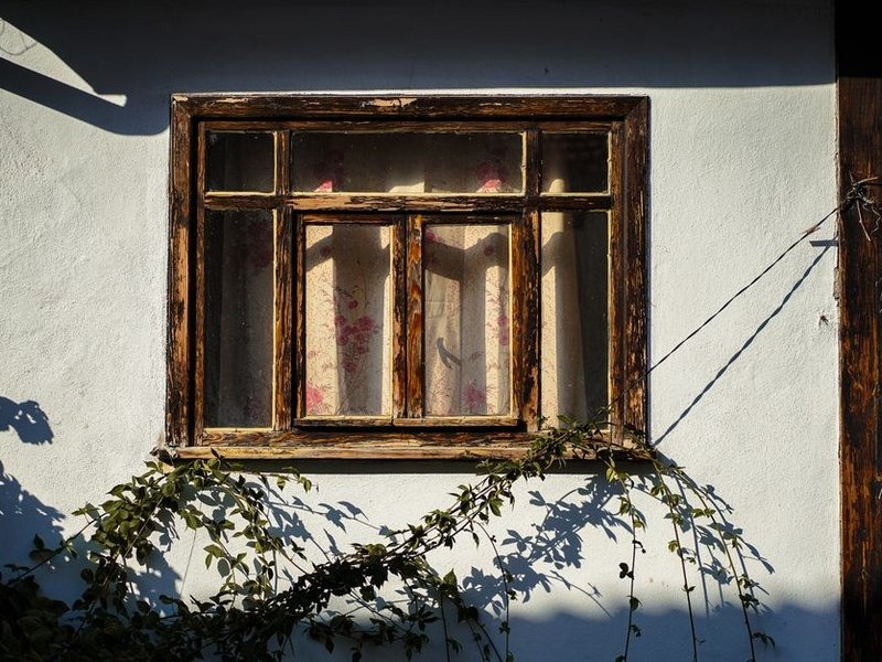 Ancienne fenêtre en bois à petits carreaux d'une maison du bourg-centre de Vaugneray avant restauration