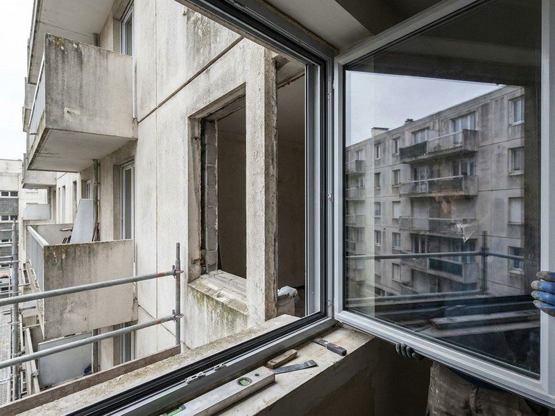 Pose d'une fenêtre à double vitrage isolant sur une façade béton de grand ensemble à Vénissieux pour le confort thermique et phonique