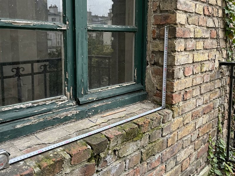 Ancienne fenêtre en bois d'origine et tableau irrégulier dans la brique d'un appartement villeurbannais