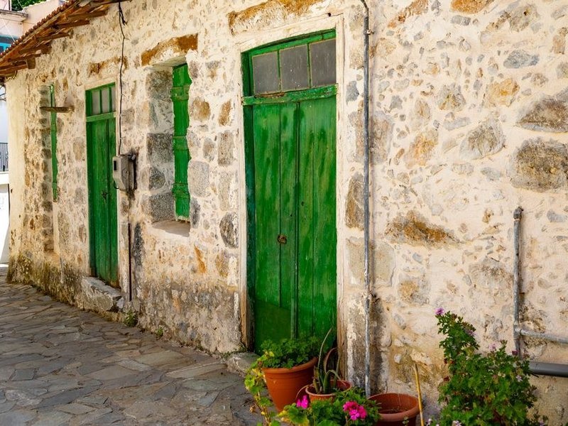Porte d'entrée ancienne en bois d'une maison de granit d'Yzeron, exposée au vent sur un seuil de pierre