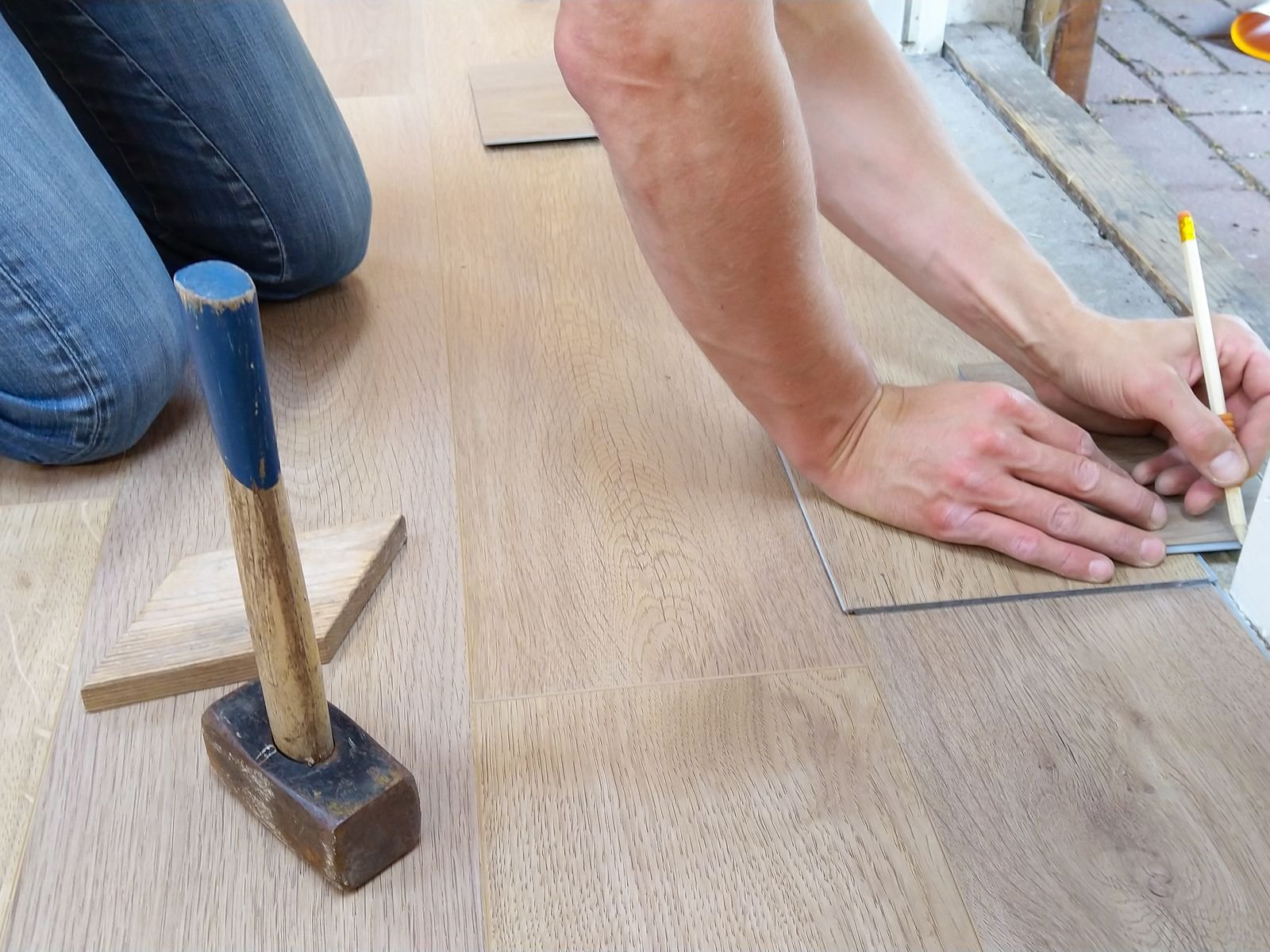 Parqueteur posant des lames de parquet bois au sol à Lyon avec cale de frappe et maillet