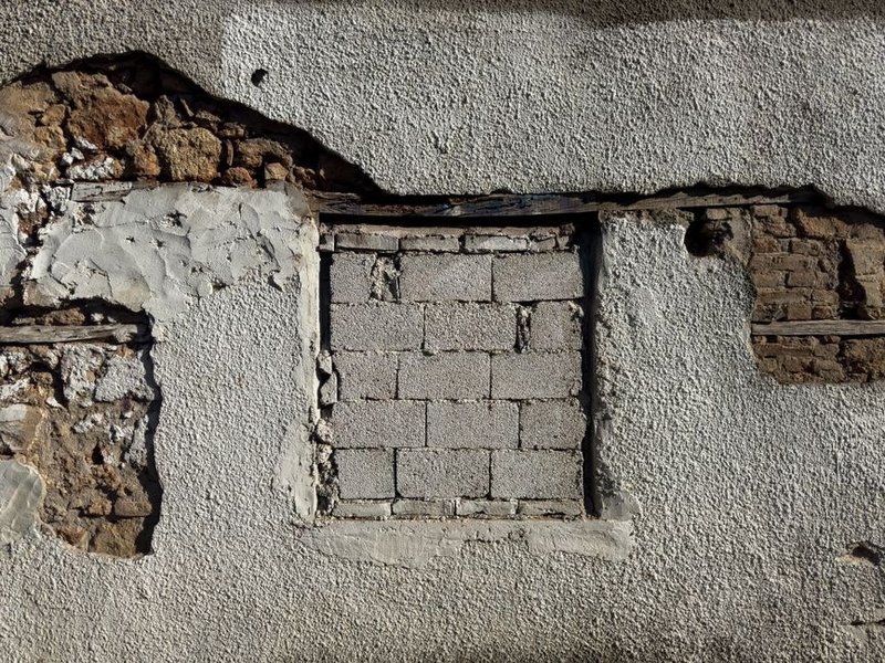Façade ensoleillée d'une maison de coteau à Bessenay dont le crépi farine, nettoyée en douceur et fixée avant un revêtement résistant aux ultraviolets
