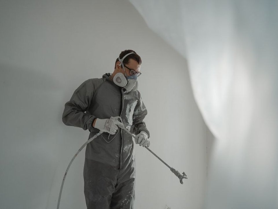 Artisan peintre laquant au pistolet une porte à panneaux dans une villa bourgeoise d'Écully, film tendu satiné sans trace sur la boiserie