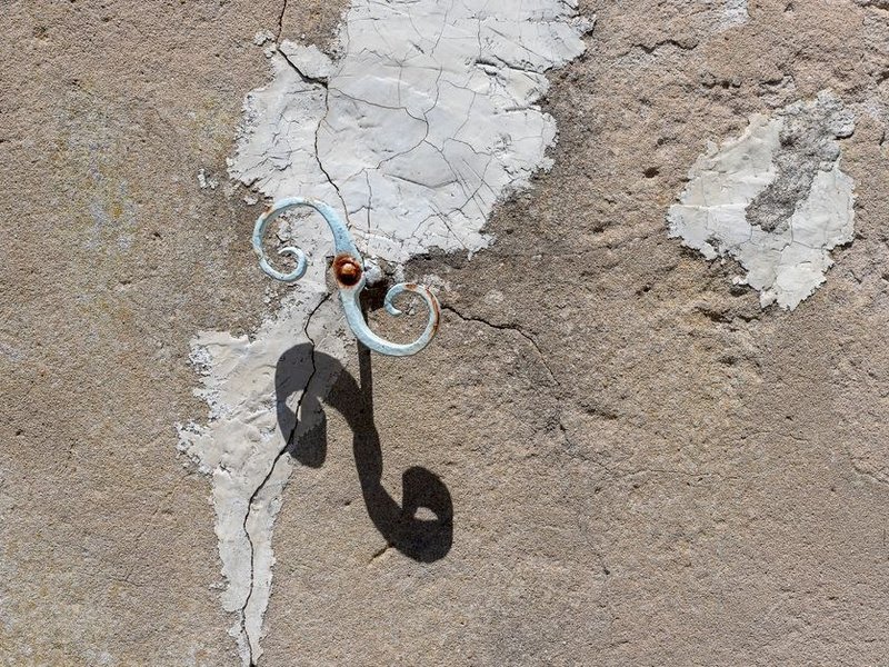 Mur en plâtre ancien fissuré et écaillé d'une maison en pierre de Fontaines-sur-Saône, à ratisser avant remise en peinture