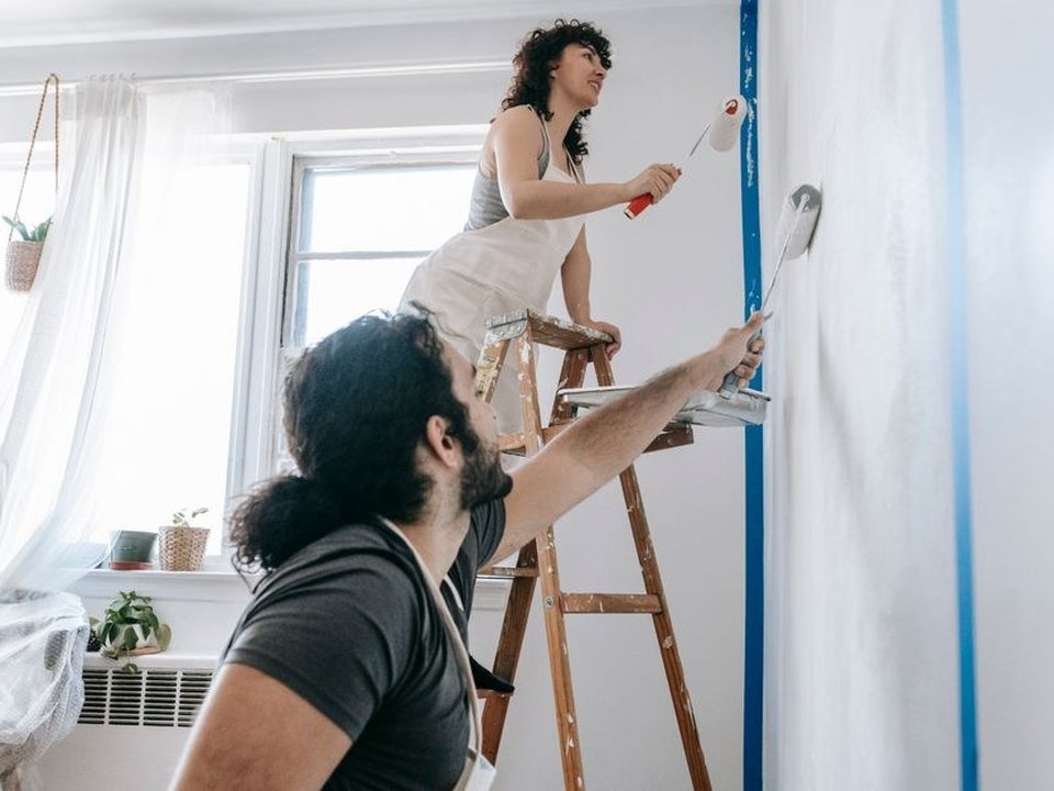 Artisan peintre appliquant à la perche une teinte choisie sur un grand mur à forte hauteur sous plafond dans un appartement bourgeois ancien d'Ainay sur la Presqu'île à Lyon 2e