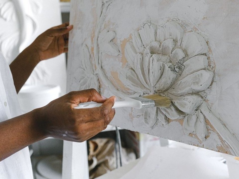 Artisan peintre rechampissant à la brosse une corniche en plâtre mouluré sous un plafond haut d'un appartement bourgeois ancien de la Préfecture à Lyon 3e