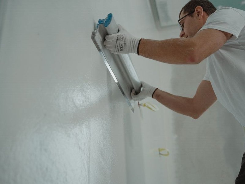 Ratissage complet d'un mur en plâtre ancien trop abîmé pour être simplement rebouché dans un logement de Saxe-Gambetta à Lyon 7e
