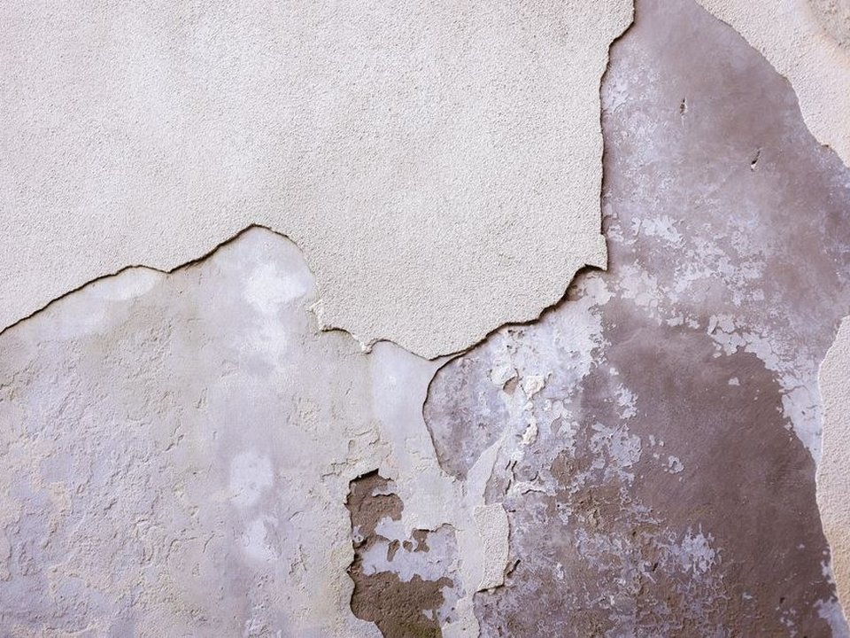 Mur plâtré ancien fissuré et écaillé d'une petite maison de ville ouvrière en brique à Saint-Fons, à reboucher avant remise en peinture, volumes serrés du sud lyonnais