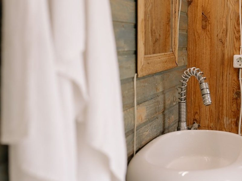 Flexible d'alimentation tressé et raccords neufs sous le plan vasque d'une salle de bain de villa à Écully