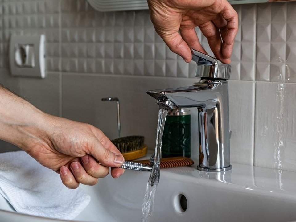 Plombier posant une robinetterie thermostatique dans une salle de bain de villa de standing à Écully