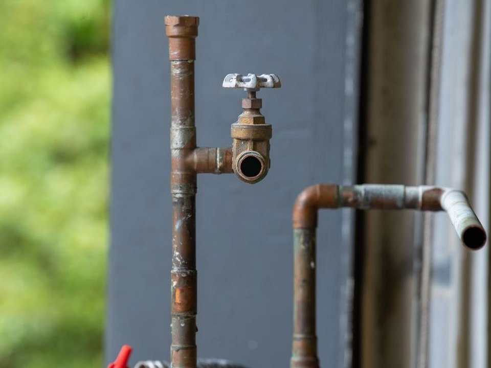 Plombier remplaçant un tuyau d'eau en acier galvanisé corrodé dans une maison de ville ancienne du vieux bourg d'Oullins