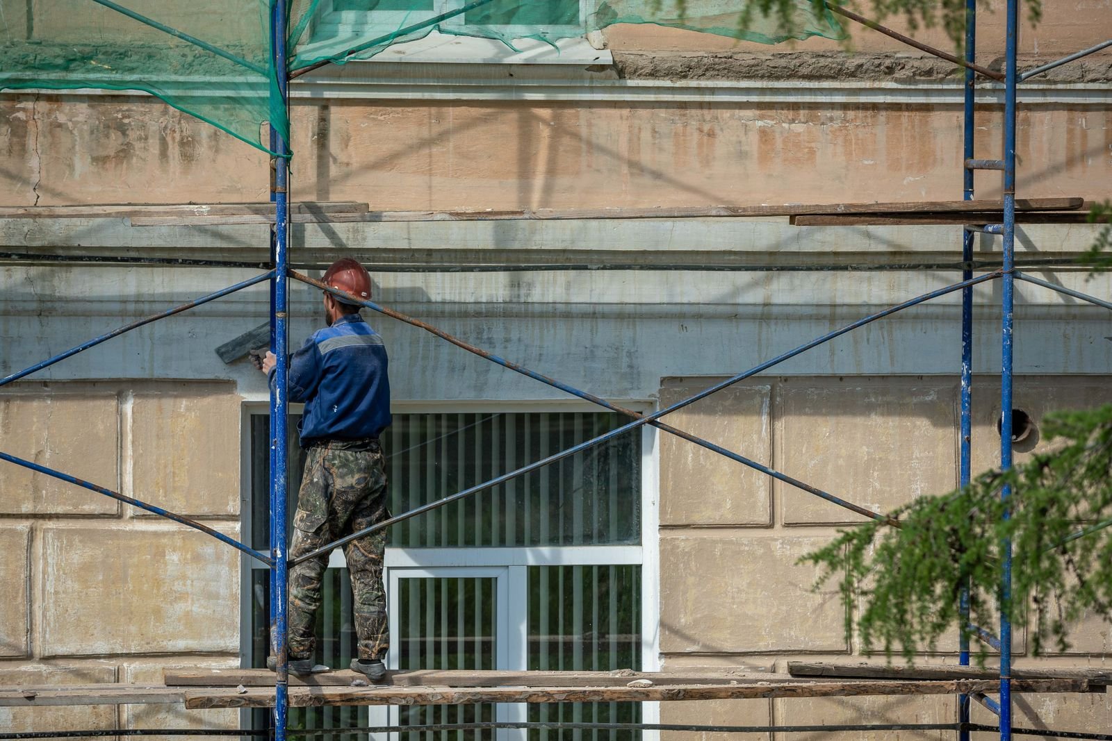 Façadier sur échafaudage appliquant un crépi de façade à Lyon