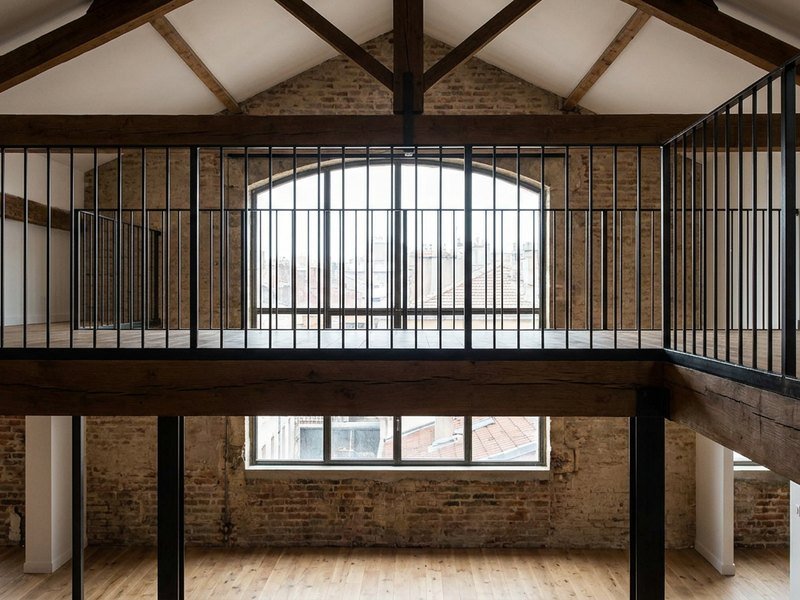 Mezzanine en bois et acier créée sous la grande hauteur d'un loft lyonnais, avec garde-corps