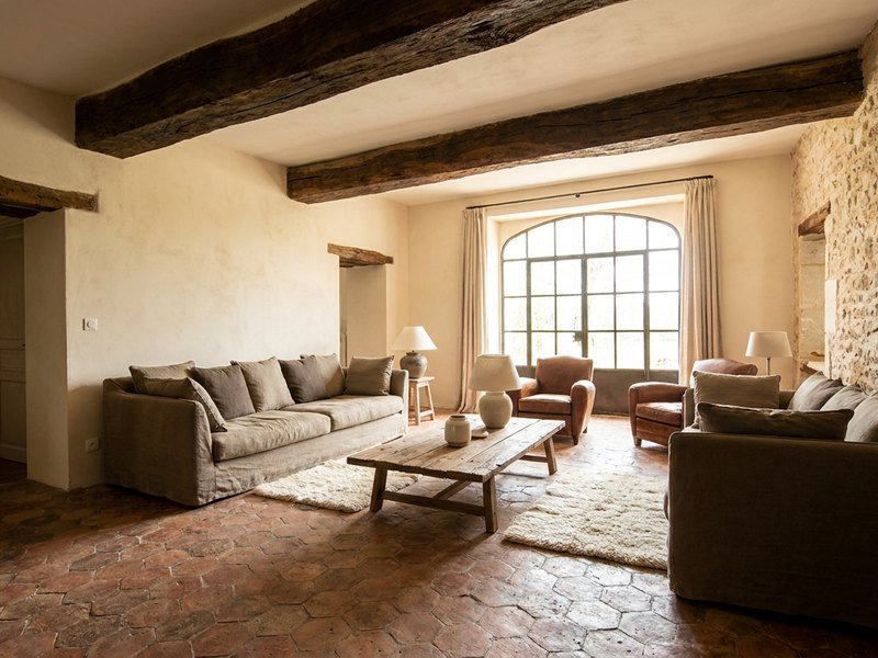 Séjour d'une maison ancienne rénovée à Lyon avec tomettes, poutres apparentes et mur en pierre conservé